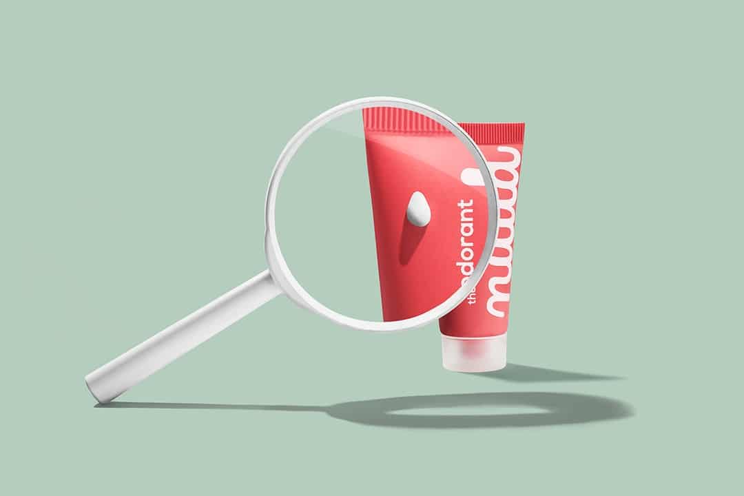 A magnifying glass inspecting a pink tube of deodorant. The tube has the word "odorant" written on it.
